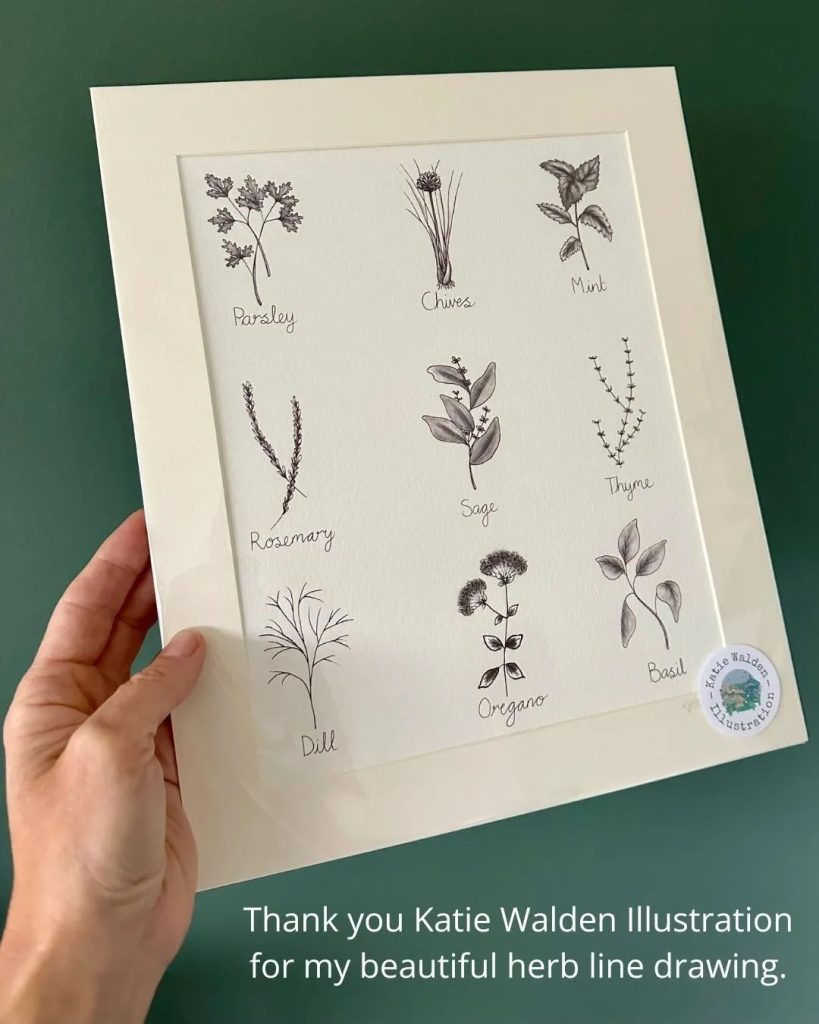 Sophie, of Sophie Seddon PR, holding a commissioned herb illustration from Katie Walden Illustration in her kitchen.