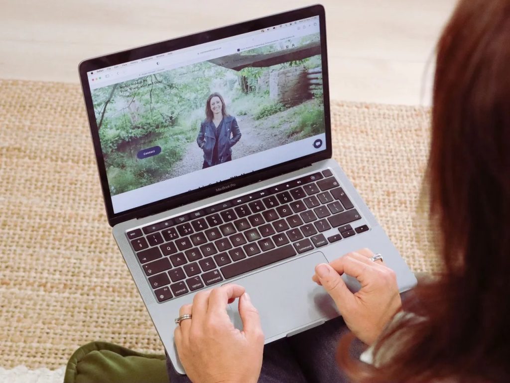 The back of Sophie, of Sophie Seddon PR, sitting, with her hands resting on her laptop.