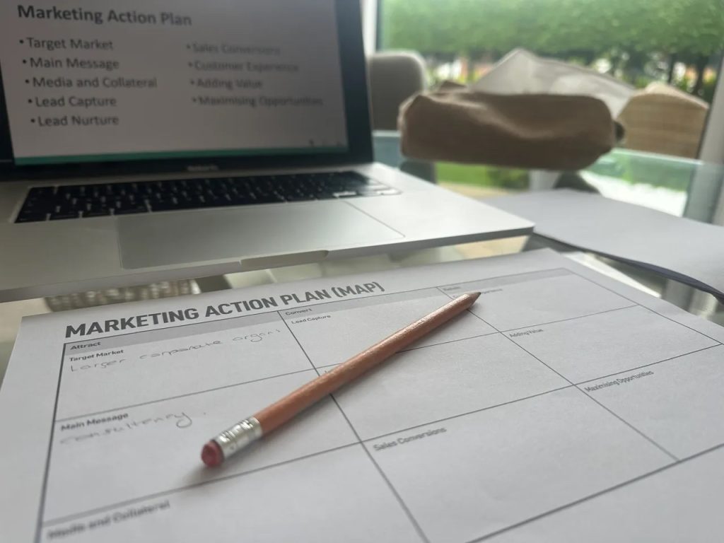 Sophie, of Sophie Seddon PR's laptop, with a marketing action plan piece of paper and pencil to make notes from the AD:VENTURE online business support workshop.